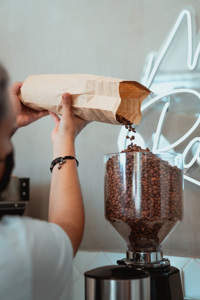 Photo of Person Pouring Coffee Beans on a Coffee Grinder